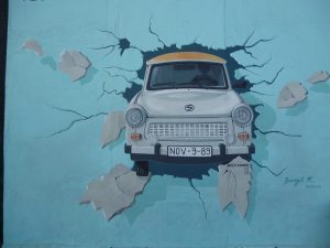 A Trabi (typical East German car) bursting through the Berlin Wall in a picture painted on the East Side Gallery in Berlin, ie a remaining part of the Berlin Wall